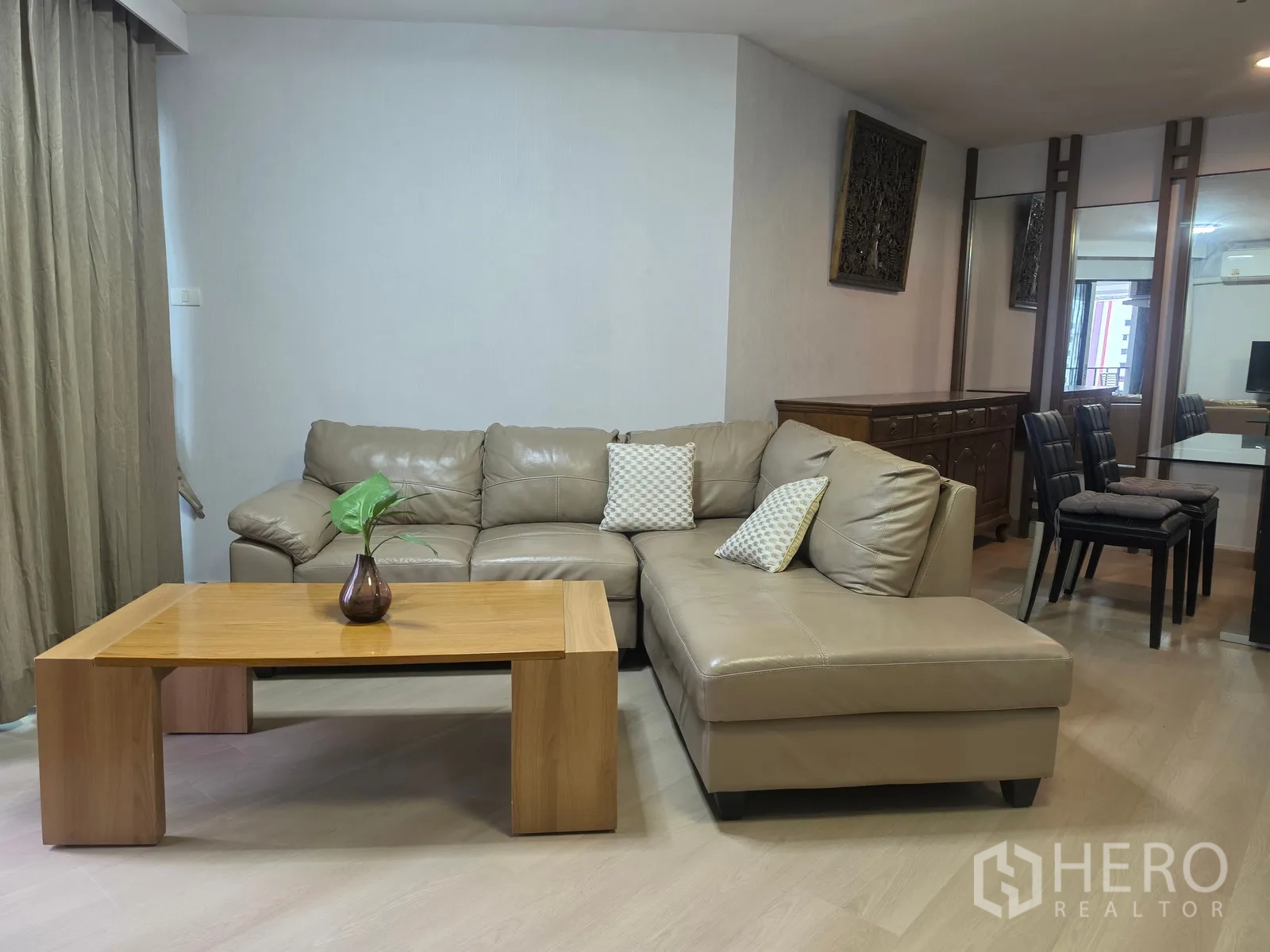 Condominium for rent in Huai Khwang, Bangkok - Living room with L-shaped leather sofa and wooden coffee table.