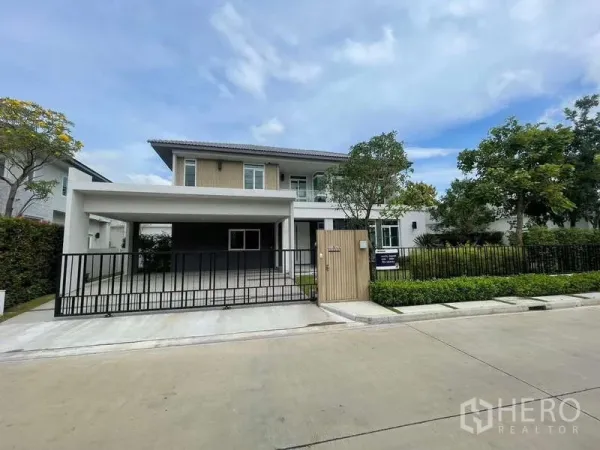 Detached House for rent or sale in Bang Bua Thong, Nonthaburi - Front elevation with double carport canopy, black metal gate, and neat landscaping.