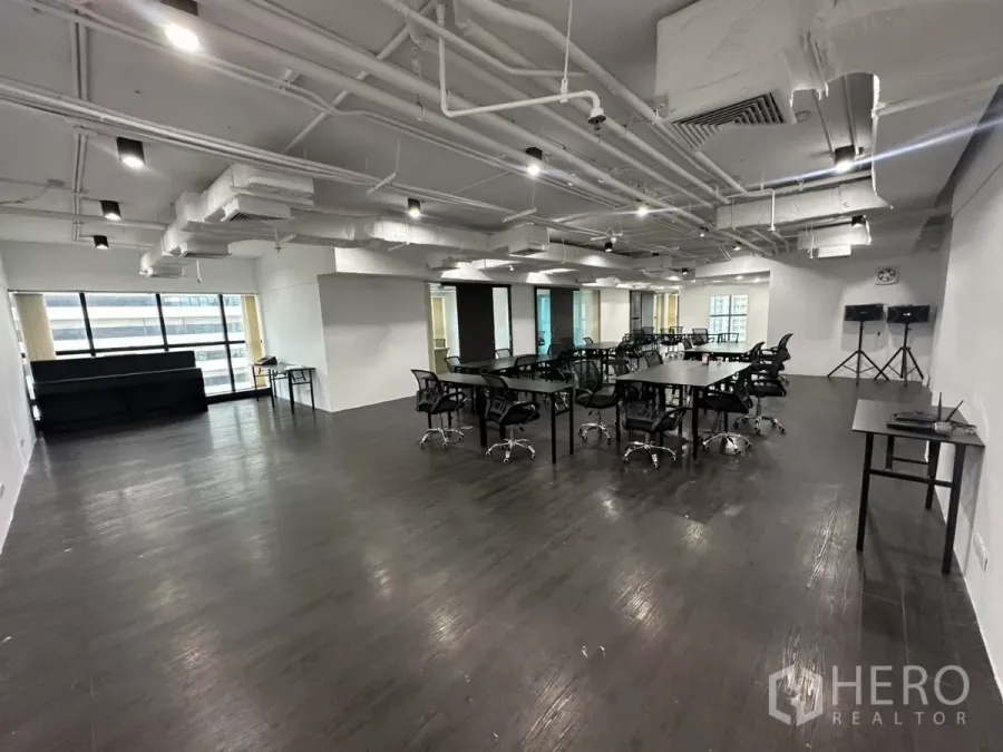 Office Space for rent in Watthana, Bangkok - Open-plan office with exposed ceiling ducts, dark floors and wide city-view windows.