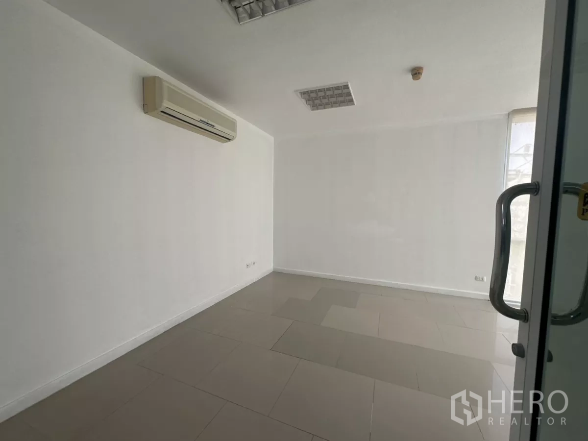 Office Space for rent in Huai Khwang, Bangkok - Compact private office with wall-mounted AC, tiled floor and a glass entry door.