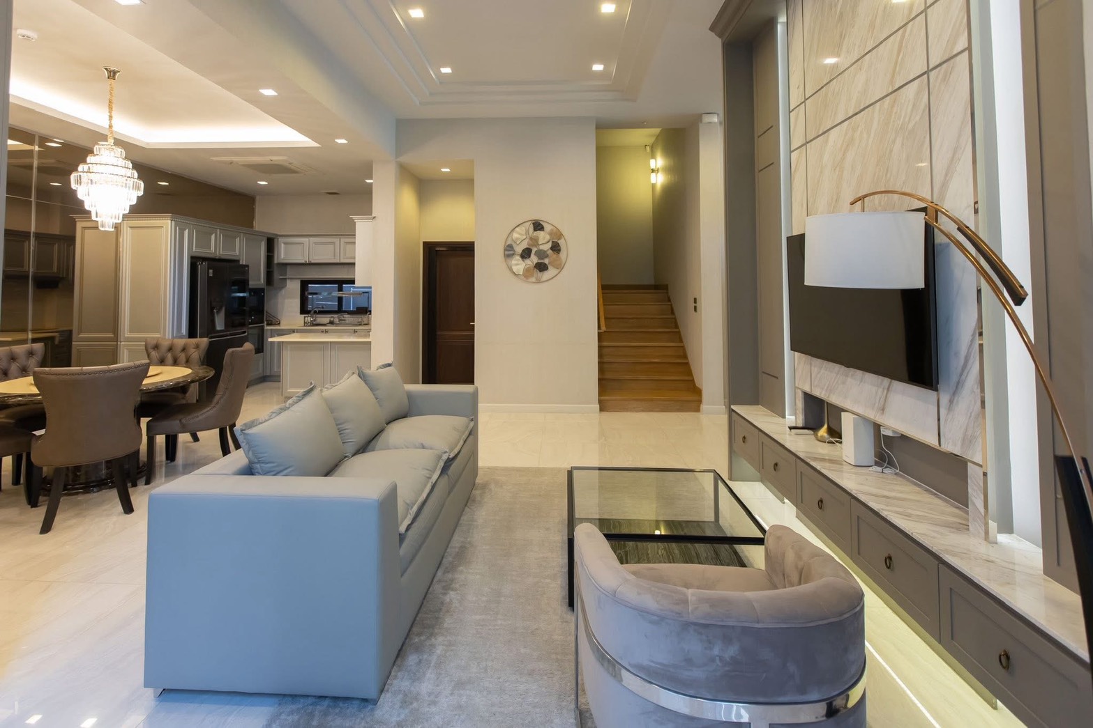 Detached House for rent in Lat Phrao, Bangkok - Open-plan living and dining connected to the kitchen, recessed lighting, and staircase.