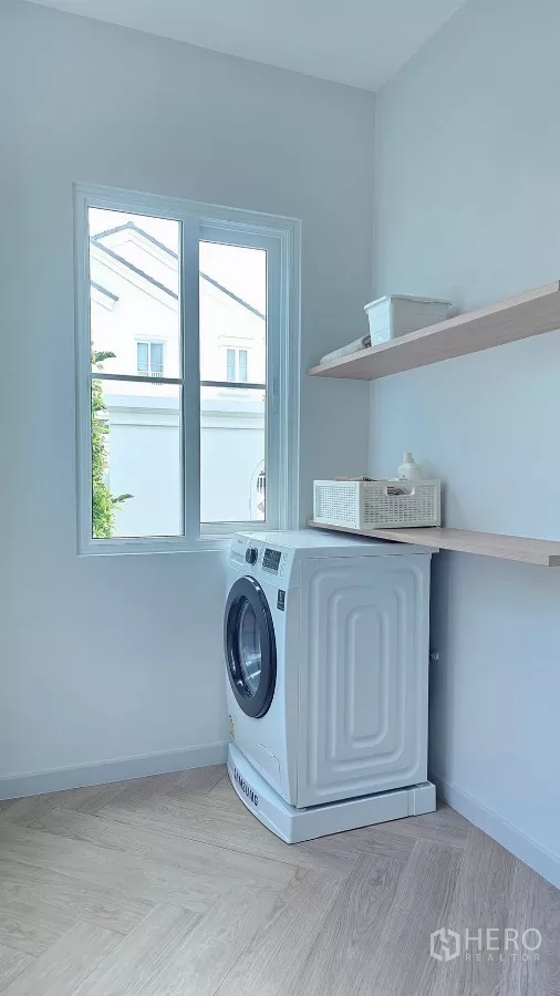 Detached House for rent in Bang Phli, Samut Prakan - Laundry room with front-load washing machine and wall shelves by a window.