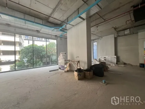 Retail Space for rent in Khlong Toei, Bangkok - Unfitted shop interior with central column, blue pipes, and full‑height windows facing the street.