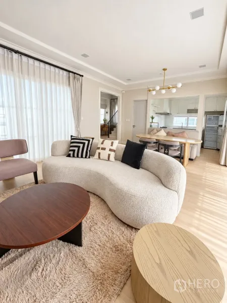 独栋房屋 for rent in Bang Phli, Samut Prakan - 开放式客餐厅，弧形沙发、圆几与后方厨房。