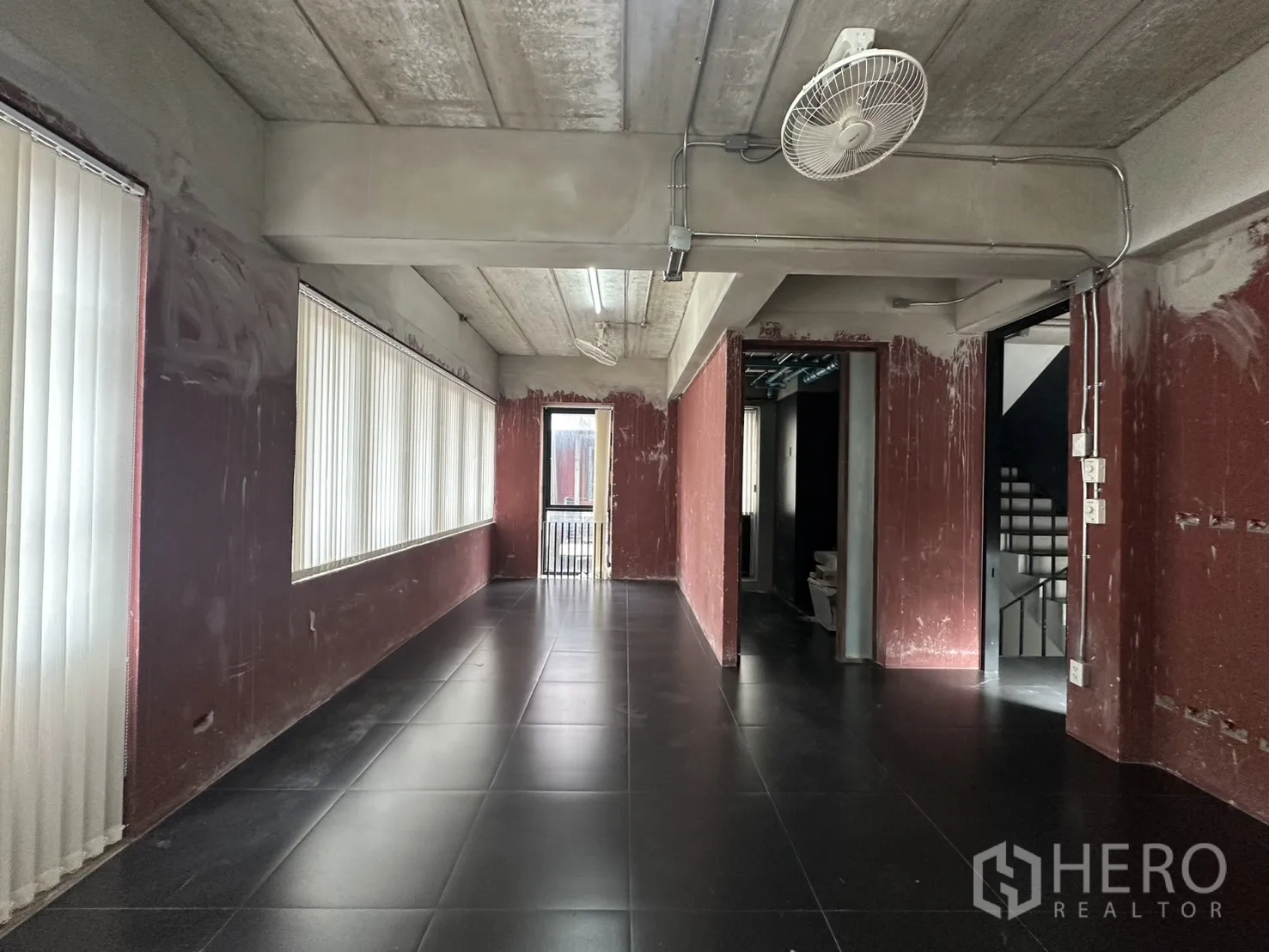 带办公室的家 for rent in Pathum Wan, Bangkok - 长形开放楼层，酒红色墙面、吊扇与整排落地窗配百叶。