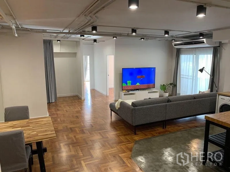 公寓 出租在Watthana, Bangkok - 宽敞客厅，开放式布局，沙发与电视，通向阳台。