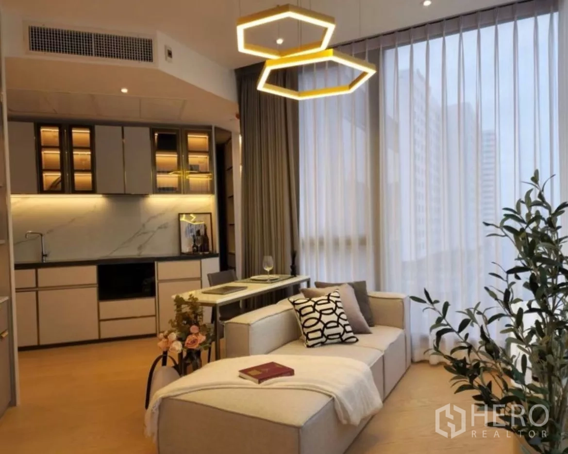 Condominium for rent in Din Daeng, Bangkok - Modern living room with open kitchen, marble backsplash, and geometric pendant lights in a Bangkok condo.