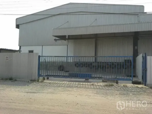 Warehouse for rent in Chon Buri - Gated metal-clad warehouse exterior with covered loading bay in Si Racha.