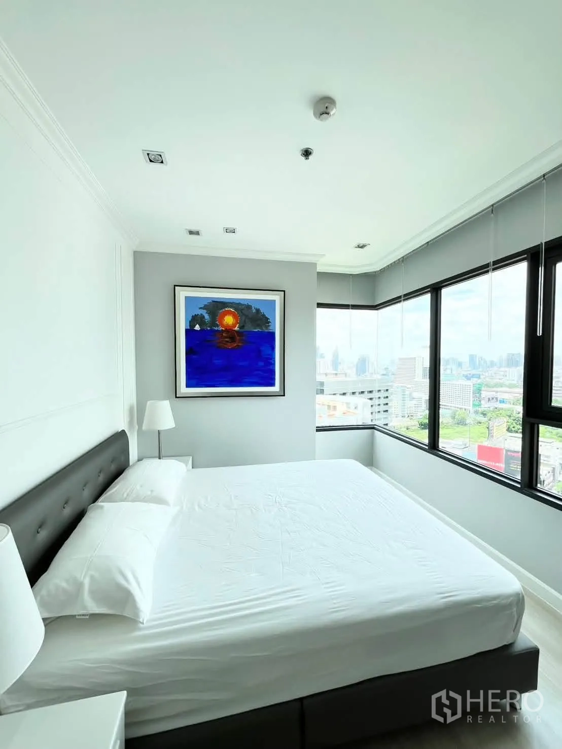 Condominium for rent in Pathum Wan, Bangkok - Corner bedroom with wraparound windows and a city view.