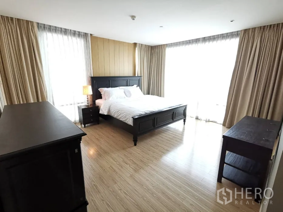 公寓 出租在Watthana, Bangkok - 采光良好的主卧，深色木床与家具，落地窗与窗帘，木地板。