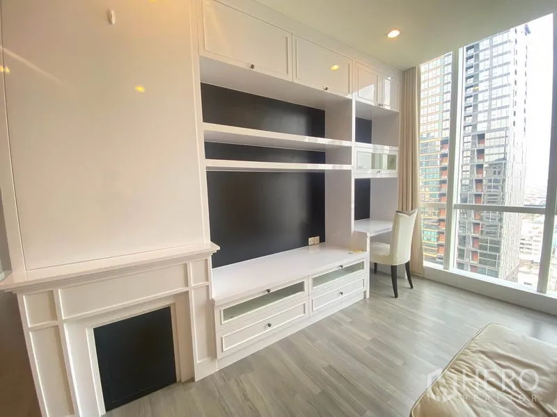 Condominium for rent in Bang Rak, Bangkok - Close-up of custom white shelving and TV wall with a study nook beside a large window.