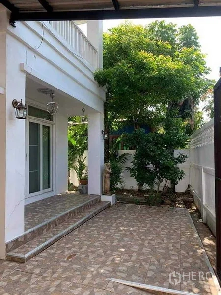 Detached House for sale in Sai Mai, Bangkok - Shaded side patio with tiled terrace, white exterior walls and mature trees.