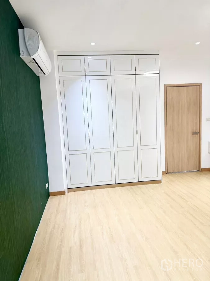 带办公室的家 出租或出售在Wang Thonglang, Bangkok - 卧室带绿色强调墙、白色衣柜与木地板。