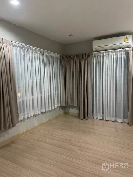 Detached House for sale in Khlong Toei, Bangkok - Corner master bedroom with sheer curtains, wood floor and air conditioner.