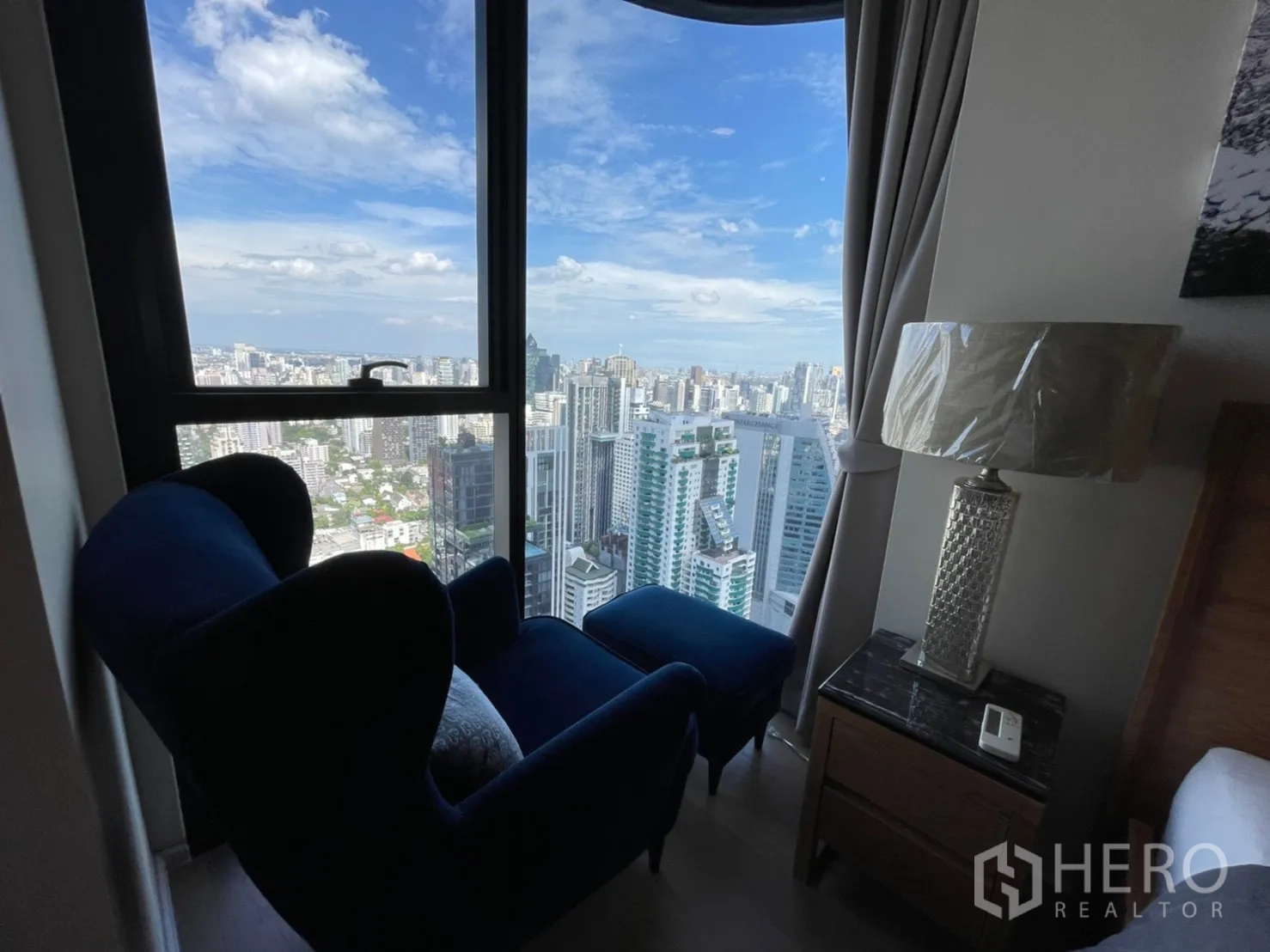 คอนโด for rent in Watthana, Bangkok - เก้าอี้นั่งเล่นสีน้ำเงินข้างหน้าต่าง ชมวิวสกายไลน์กว้าง