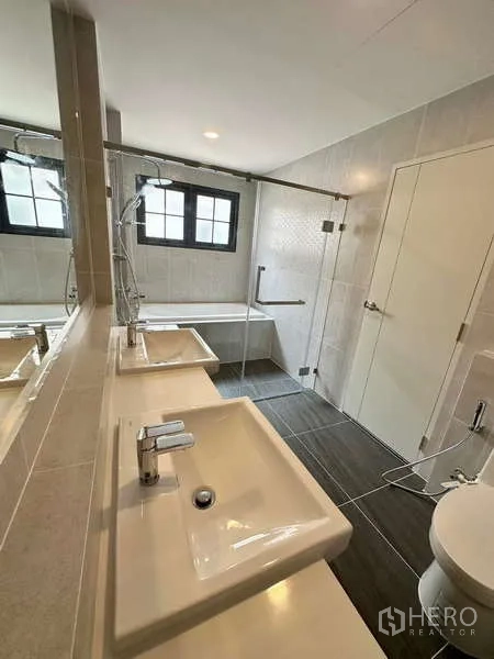 Detached House for rent in Bang Phli, Samut Prakan - Contemporary bathroom with double vanity, large mirror and glass-enclosed shower.