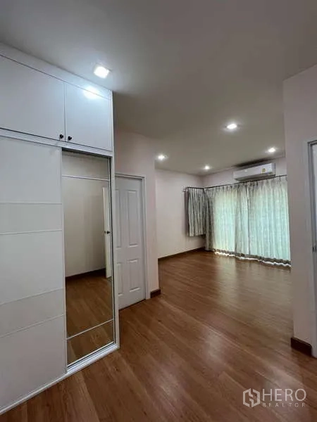 Detached House for rent or sale in Khan Na Yao, Bangkok - Spacious master bedroom with wood floors, built-in wardrobe and large windows.