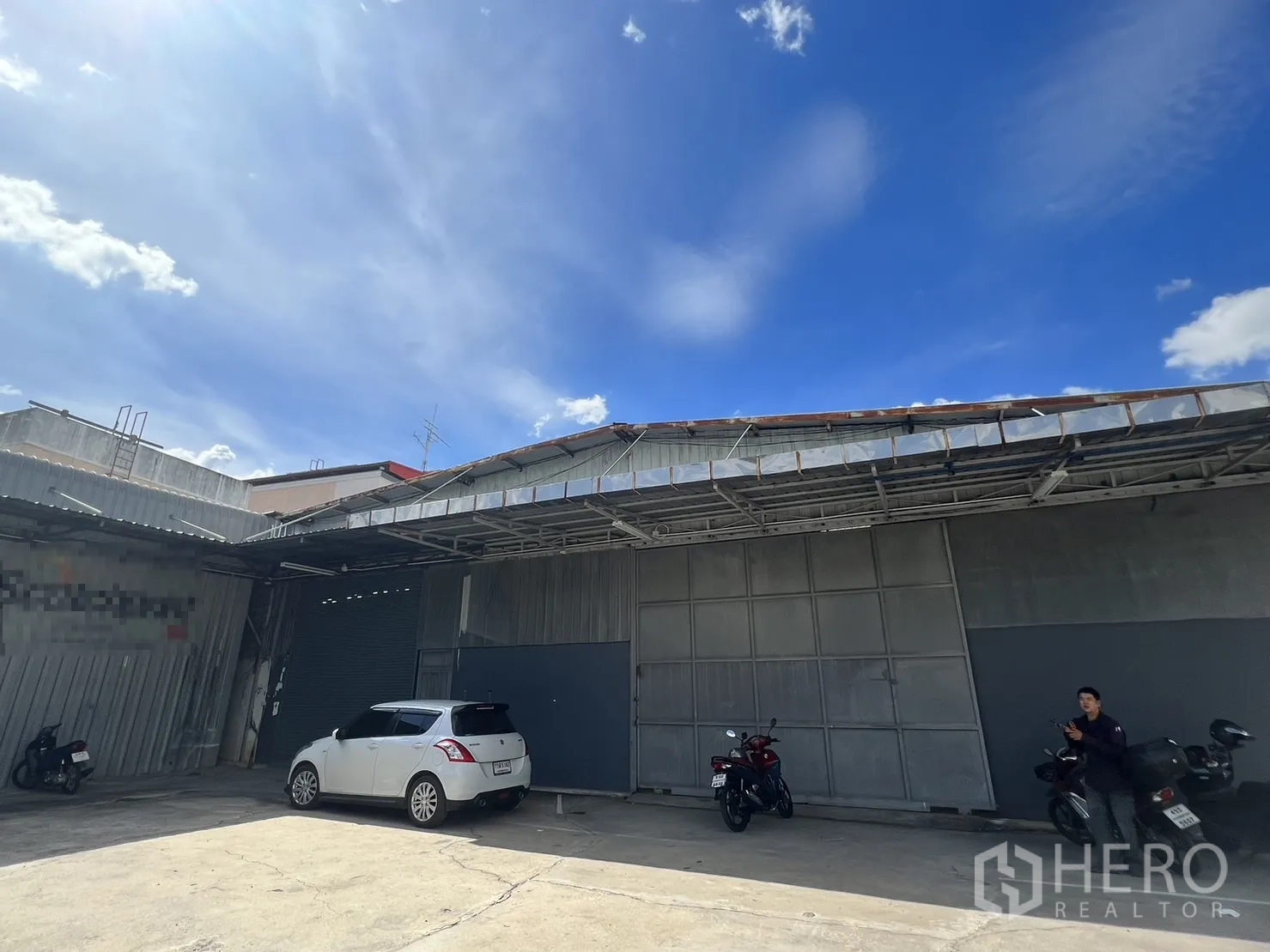 货栈 出租在Suan Luang, Bangkok - 仓库正面，超宽卷帘门与铺装前院停车区。