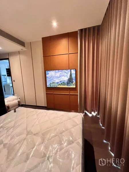 Condominium for rent in Watthana, Bangkok - Bedroom angle with wall-mounted TV, tan paneling, and full-length curtains.