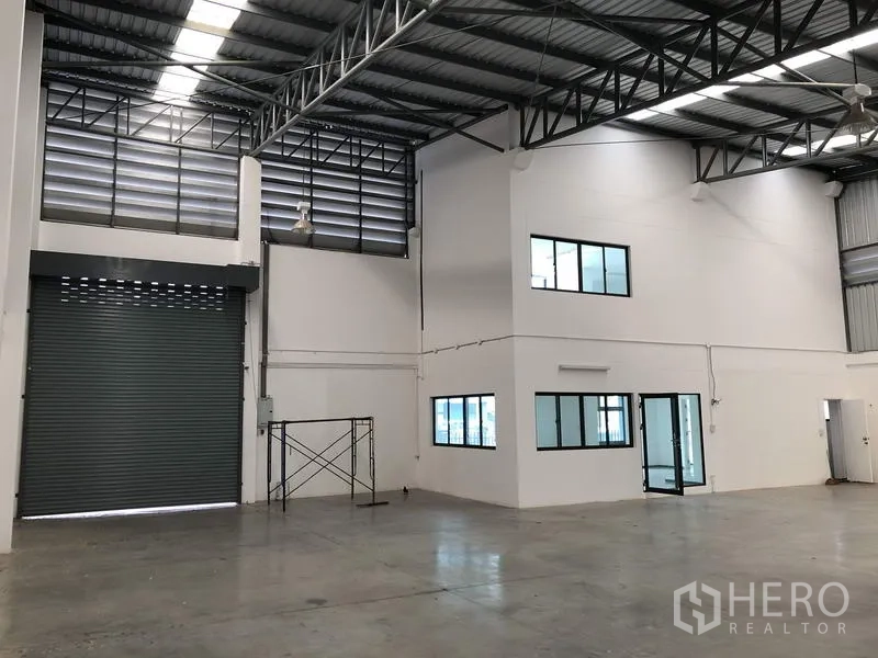 Factory for rent or sale in Pathum Thani - Empty warehouse bay with tall roller door and internal two-storey office box.