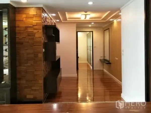 Condominium for rent or sale in Watthana, Bangkok - Entry corridor with recessed lighting, wooden feature wall and floating display shelves.