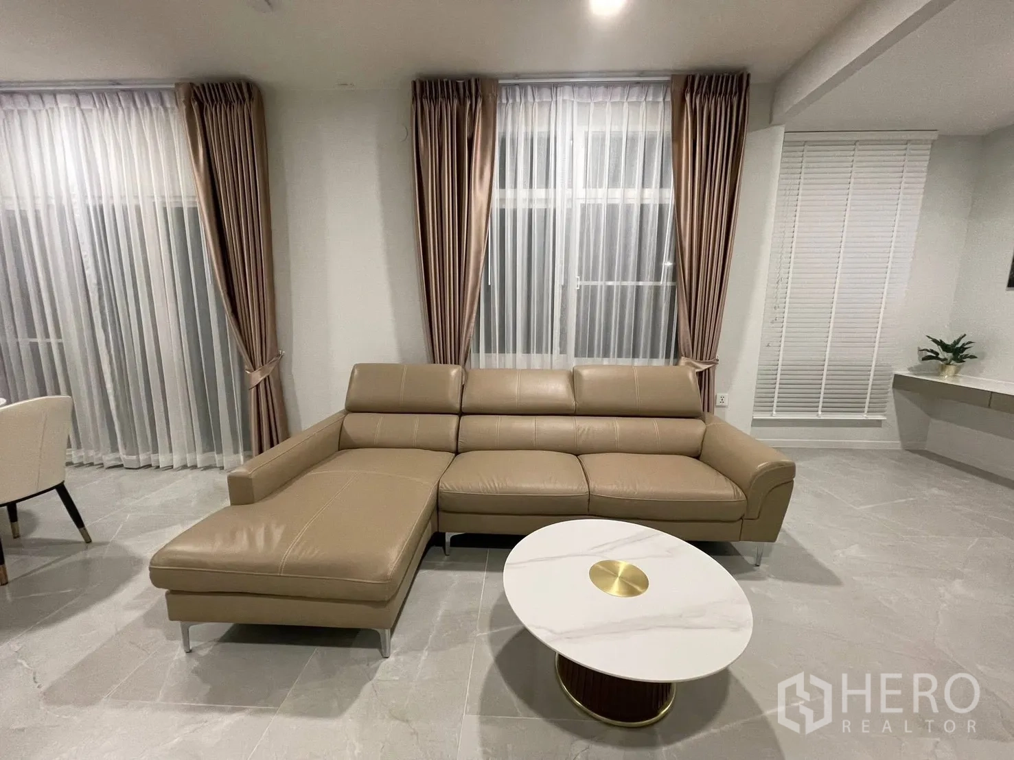 独栋房屋 for rent in Prawet, Bangkok - 皮质转角沙发与圆形大理石茶几，临近高窗。