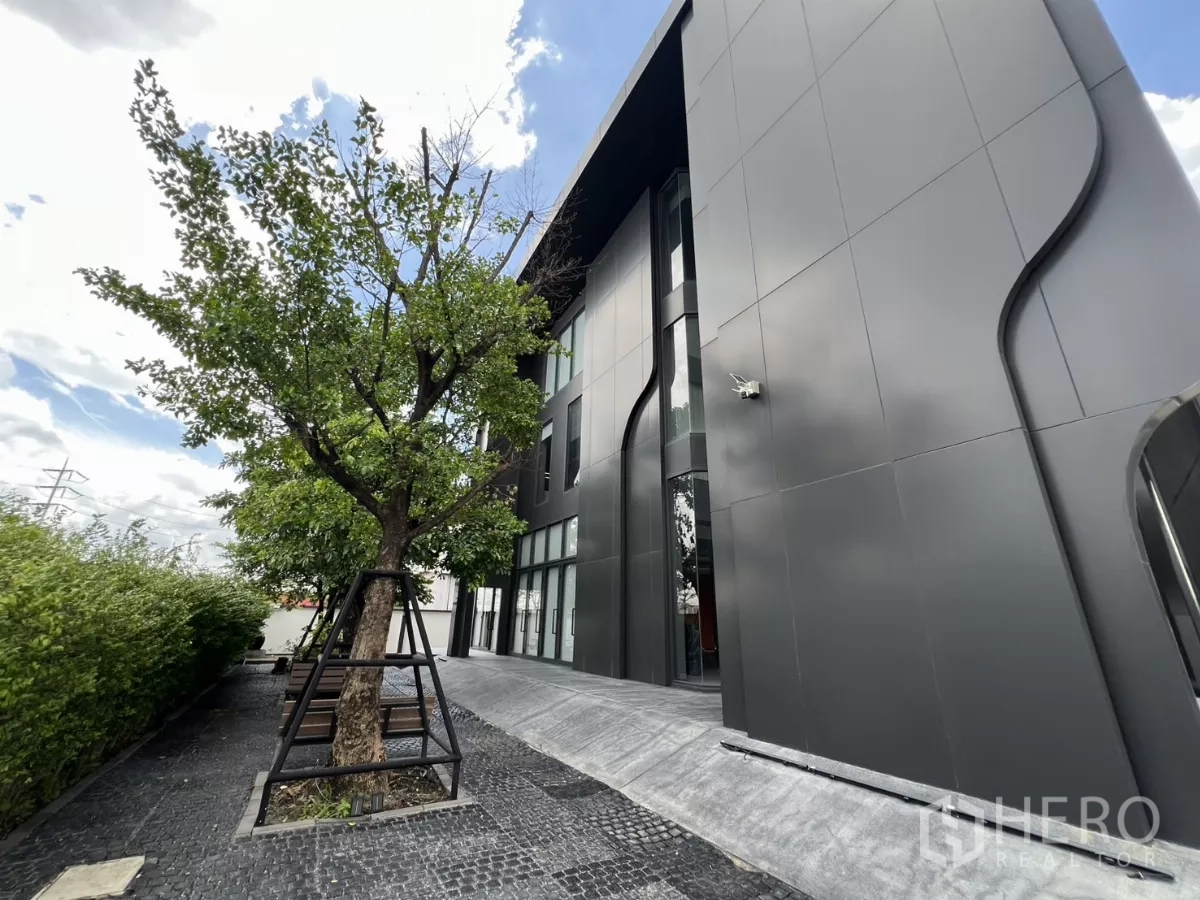 货栈 出售在Lat Krabang, Bangkok - 建筑侧边景观，有树木与黑色金属板立面。