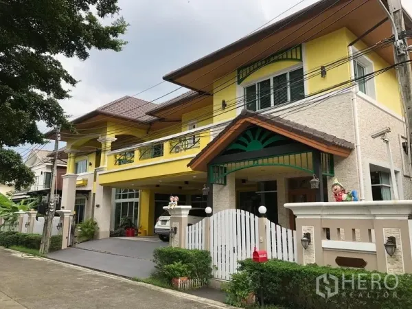 Detached House for sale in Wang Thonglang, Bangkok - Two-storey yellow detached house with gated entrance and a covered three-car garage in a secure compound.