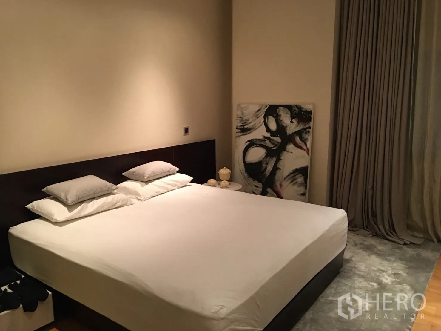 Condominium for rent or sale in Bang Rak, Bangkok - Cozy bedroom with king-size bed, neutral walls, floor-to-ceiling curtains and abstract artwork.