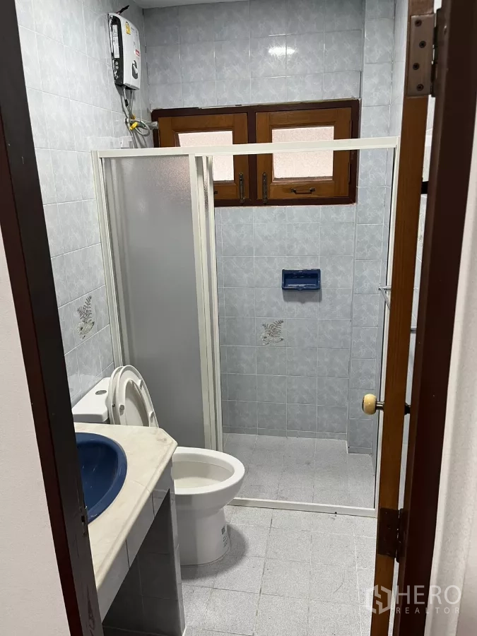 Detached House for rent in Watthana, Bangkok - Bathroom with shower enclosure, toilet and vanity beneath small windows.
