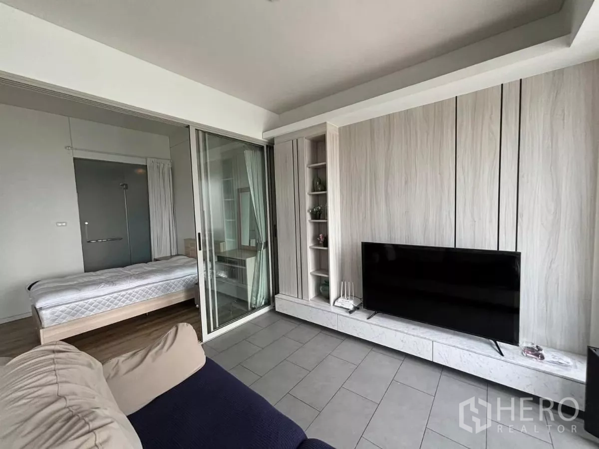 Condominium for rent or sale in Phaya Thai, Bangkok - Living room facing a sliding glass partition revealing a bedroom and the TV feature wall.