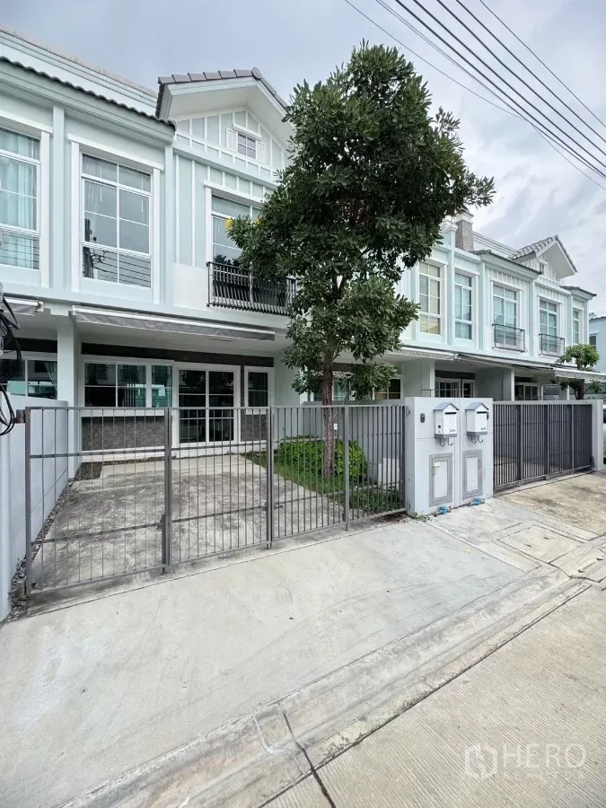 联排别墅 出租在Prawet, Bangkok - 现代联排别墅外观，金属围栏、车道与前院树木。