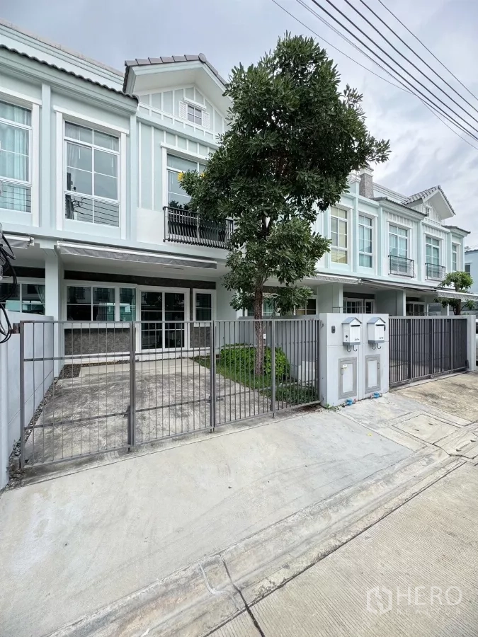 联排别墅 出租在Prawet, Bangkok - 现代联排别墅外观，金属围栏、车道与前院树木。
