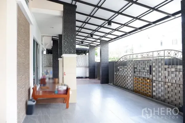 Detached House for sale in Saphan Sung, Bangkok - Covered terrace at the front with tiled floor, dark columns and a metal entry gate.