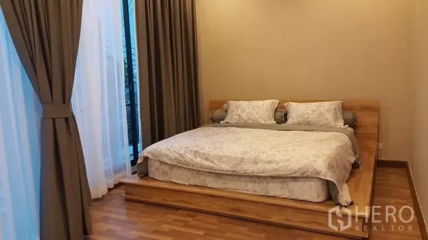 Detached House for sale in Samut Prakan - Cozy bedroom with a platform king bed and full-height draped windows.