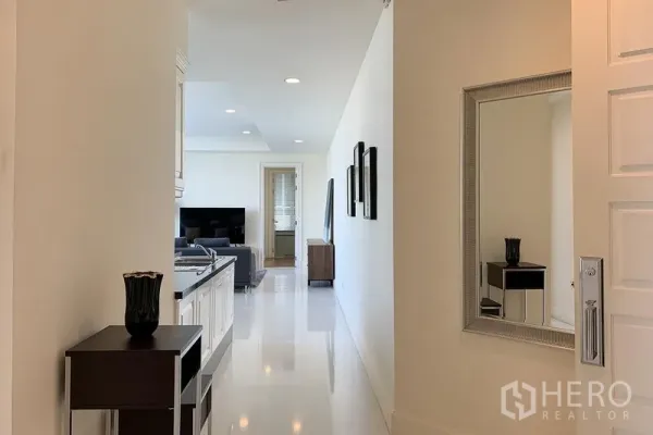 公寓 出租在Watthana, Bangkok - 明亮的入户走廊通往客厅，墙面镜子与嵌灯。