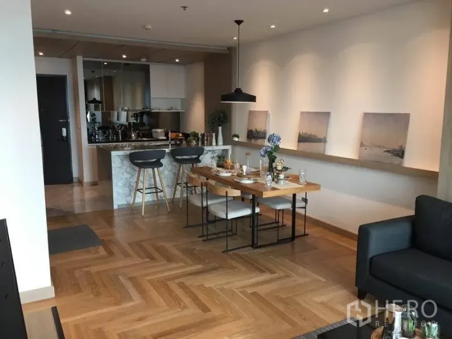 公寓 出售在Watthana, Bangkok - 宽敞开放式厨房与餐区，人字形木地板与吧台照明。