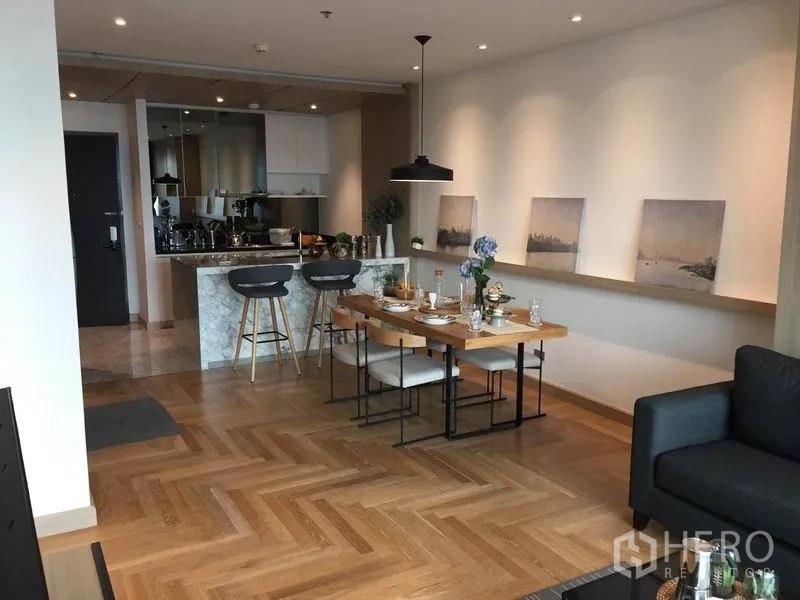 公寓 出售在Watthana, Bangkok - 宽敞开放式厨房与餐区，人字形木地板与吧台照明。