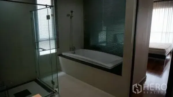 Condominium for rent or sale in Pathum Wan, Bangkok - Ensuite bathroom with a built-in bathtub beside a glass shower, view toward the bedroom
