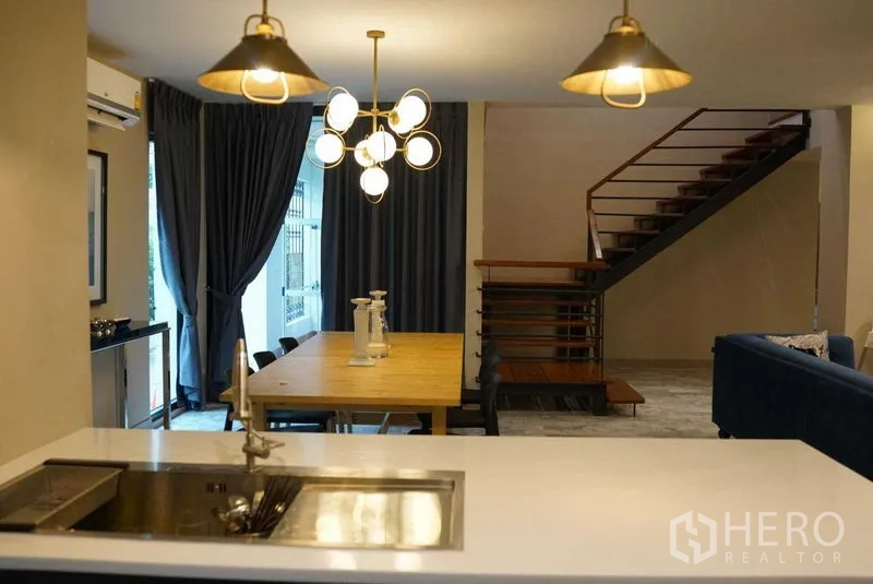 คอนโด ให้เช่าในWatthana, Bangkok - มองจากไอส์แลนด์ครัวไปยังโต๊ะอาหาร โคมไฟแขวน และบันไดสมัยใหม่