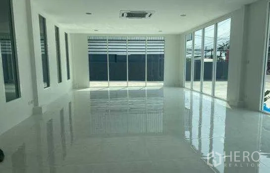 Warehouse for rent in Prawet, Bangkok - Bright office interior with glossy white tiles, floor-to-ceiling windows, and ceiling cassette air-conditioner.