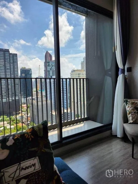 公寓 出租在Watthana, Bangkok - 推拉玻璃门通往阳台，可眺望市中心高楼与蓝天白云。