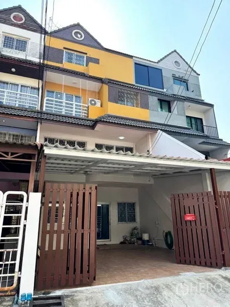 Townhouse for rent or sale in Suan Luang, Bangkok - Street view of colorful townhouse row with covered parking bay