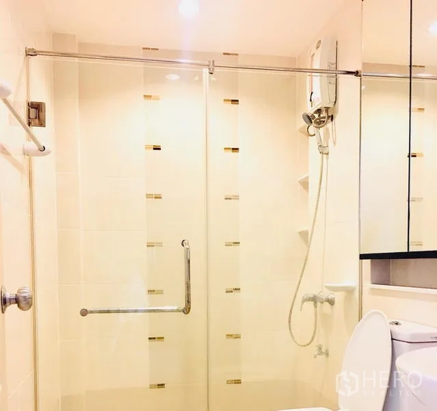 联排别墅 出租在Prawet, Bangkok - 浴室设玻璃淋浴间、热水器和镜柜，浅色瓷砖。