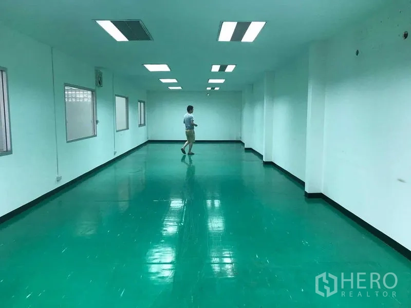 Warehouse for rent in Bang Phli, Samut Prakan - Long office or production room with glossy green epoxy floor and bright fluorescent lighting.