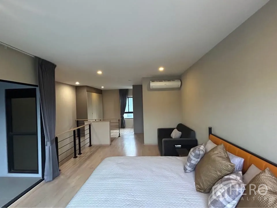 Townhouse for rent in Suan Luang, Bangkok - Spacious master suite with king bed, sofa, air conditioner and open loft-style railing.
