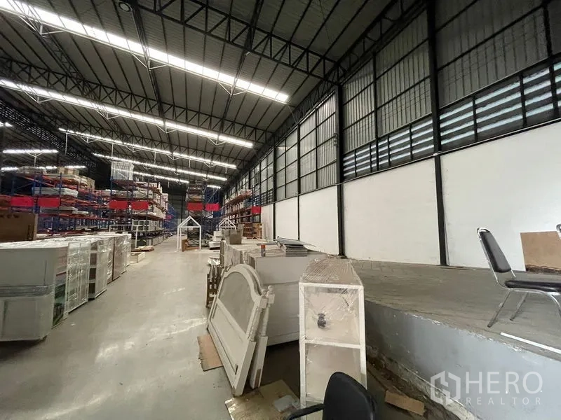 Warehouse for rent in Lat Krabang, Bangkok - Bright LED-lit aisle with elevated loading platform and storage racks inside the warehouse.