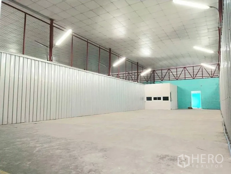 Warehouse for rent in Yan Nawa, Bangkok - Clear-span warehouse space with LED strip lighting, corrugated metal walls and marked loading area on the concrete floor.