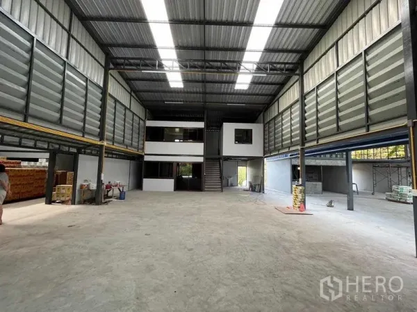 Warehouse for rent in Prawet, Bangkok - Spacious warehouse interior with high clear-span roof, skylights, and mezzanine offices.