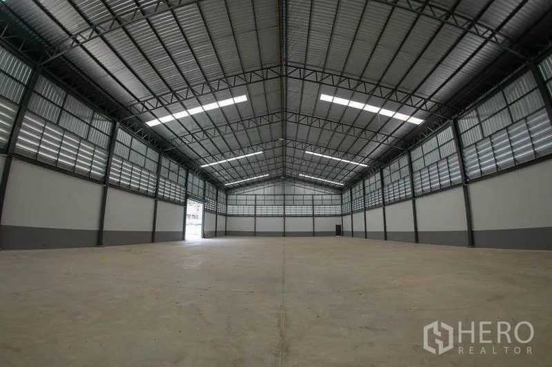 Warehouse for sale in Krathum Baen, Samut Sakhon - Symmetrical shot of empty warehouse hall with ventilated cladding and skylights.